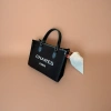 CHARES PARIS black handbag with white logo, black leather handle and beige sofa scene details Picture